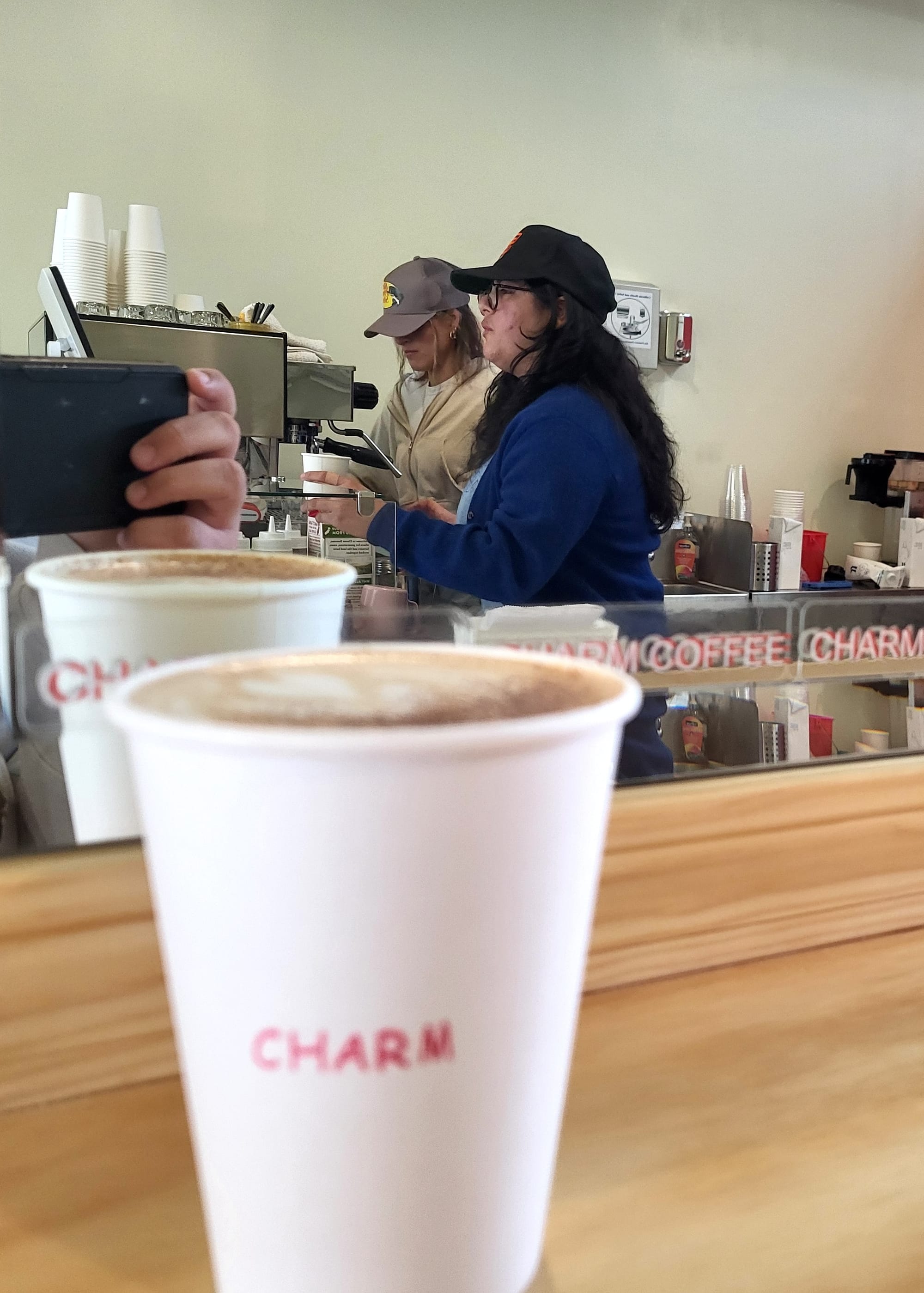 Coffee cop in foregroun with workers in the background making coffee.